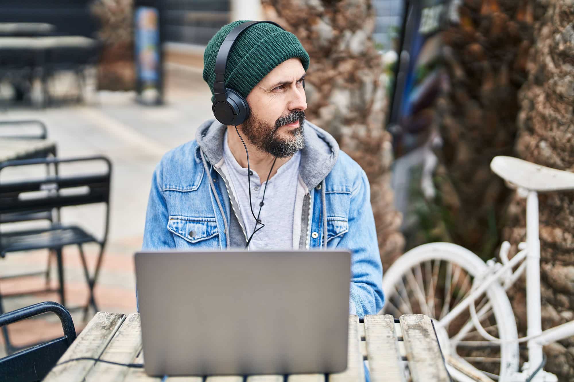Man sitting outside with headphones and laptop