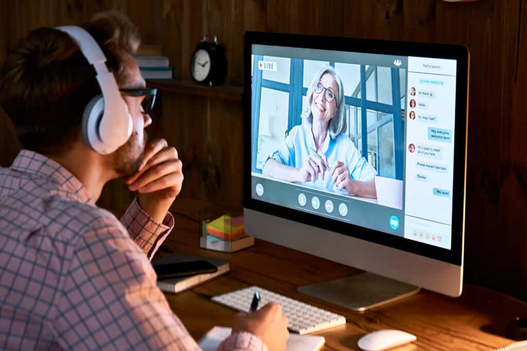 Male student wearing headphones taking online course training, watching webinar, remote seminar university class, virtual learning with social distance web teacher, tutor or coach on computer screen